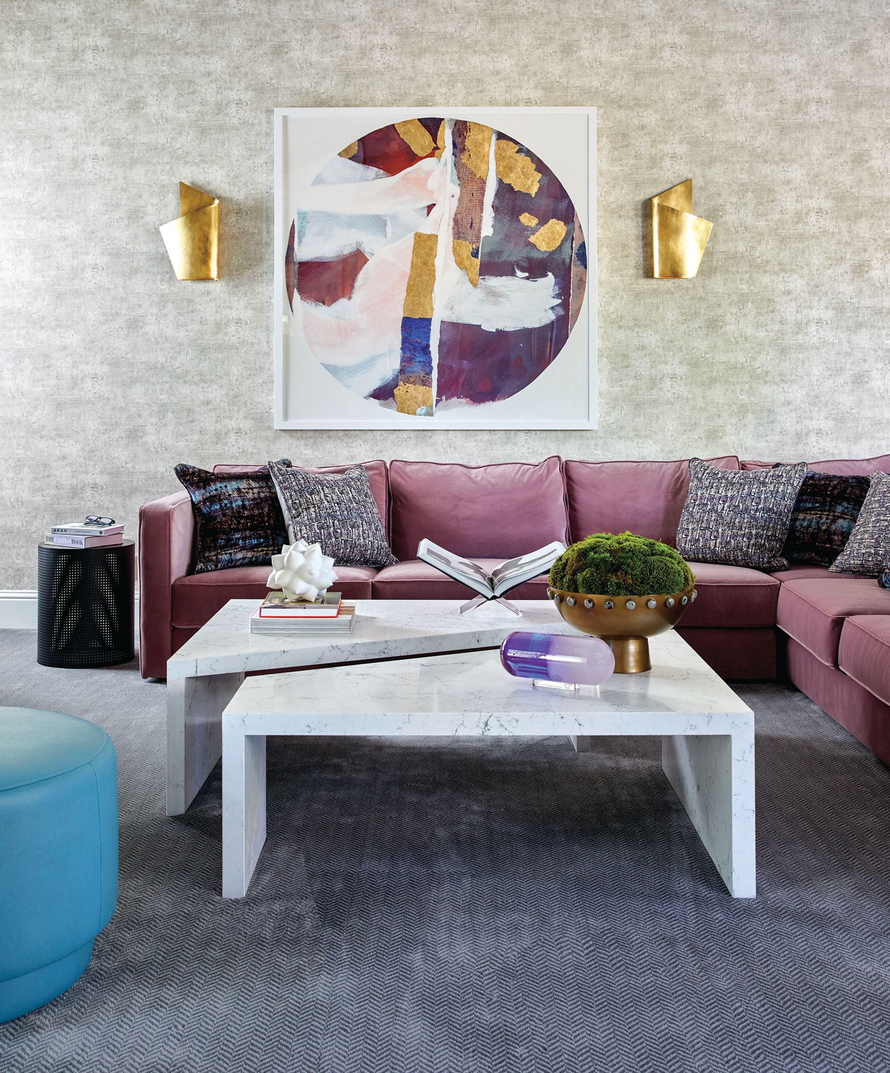 A two-tiered quartz table by Britany Simon Design House pairs nicely with a bold mauve velvet custom sectional. Wallpaper by Thibaut adds subtle texture to the walls and accents the oversize art piece by Zoe Bios Creative. The perforated metal side table from Noir adds some edge to the room. Photographed by Laura Moss