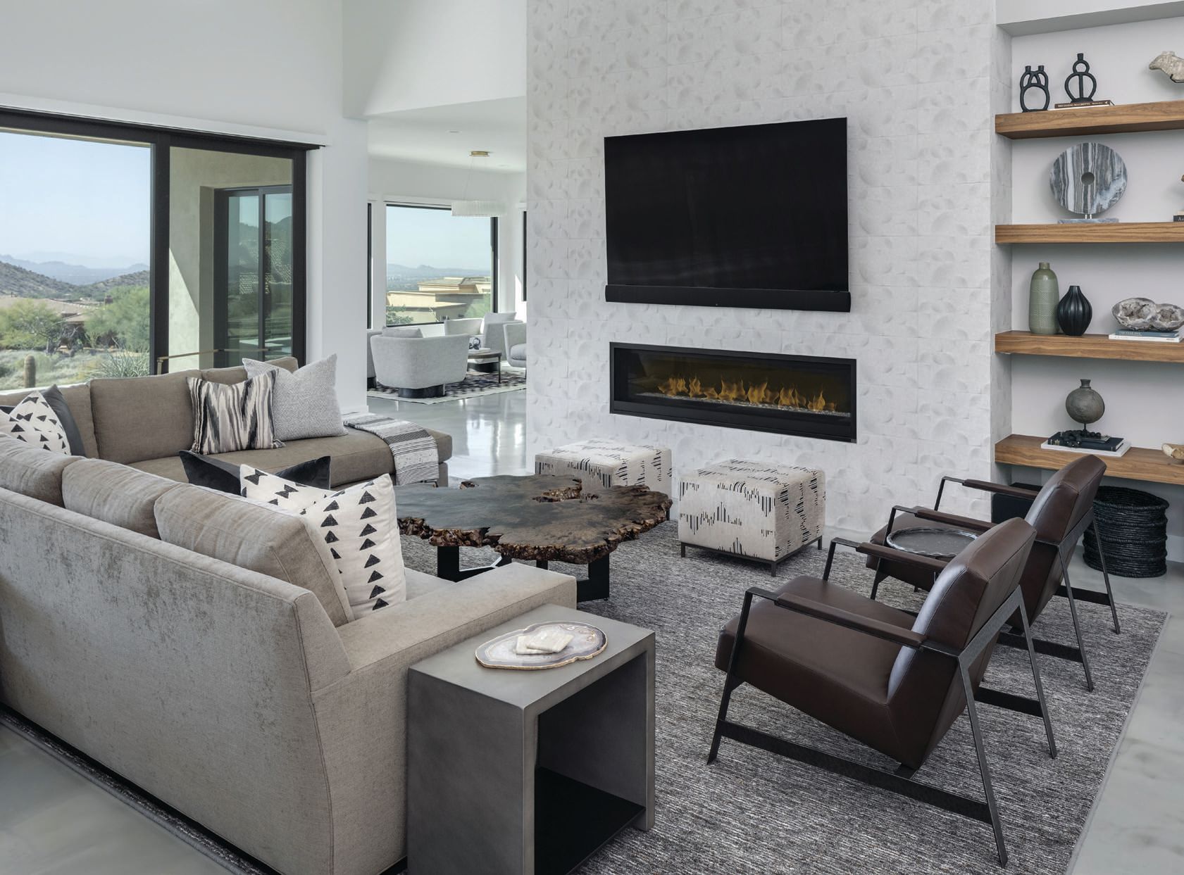 The living room is set with a plush cushioned sectional and leather accent chairs for entertaining Photographed by Drufer Photography