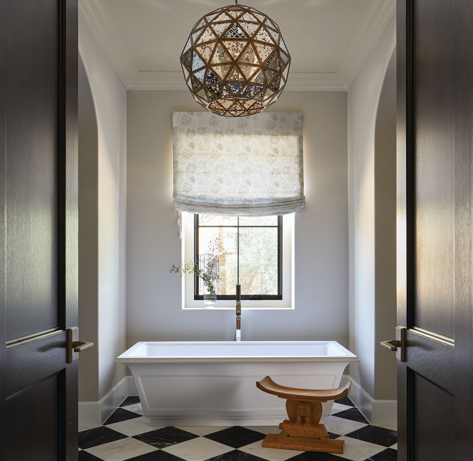 Benjamin Moore’s Winds Breath paint coats the walls in the primary bathroom, where a tub by Gessi and a pendant from Currey & Company preside. PHOTOGRAPHED BY LAURA MOSS