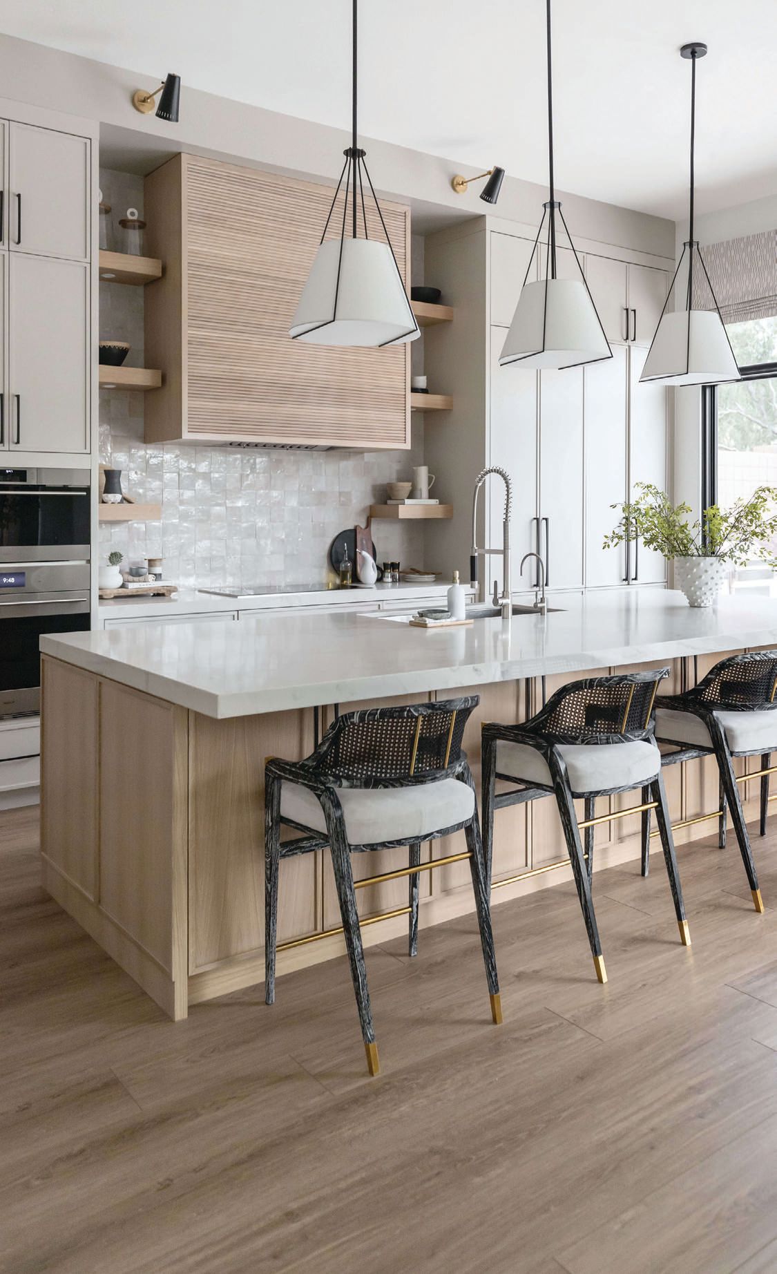 In the kitchen, a white oak island is topped with Heloise pendants from Arteriors and surrounded by stunning counter stools from Villa & House Photographed by Life Created