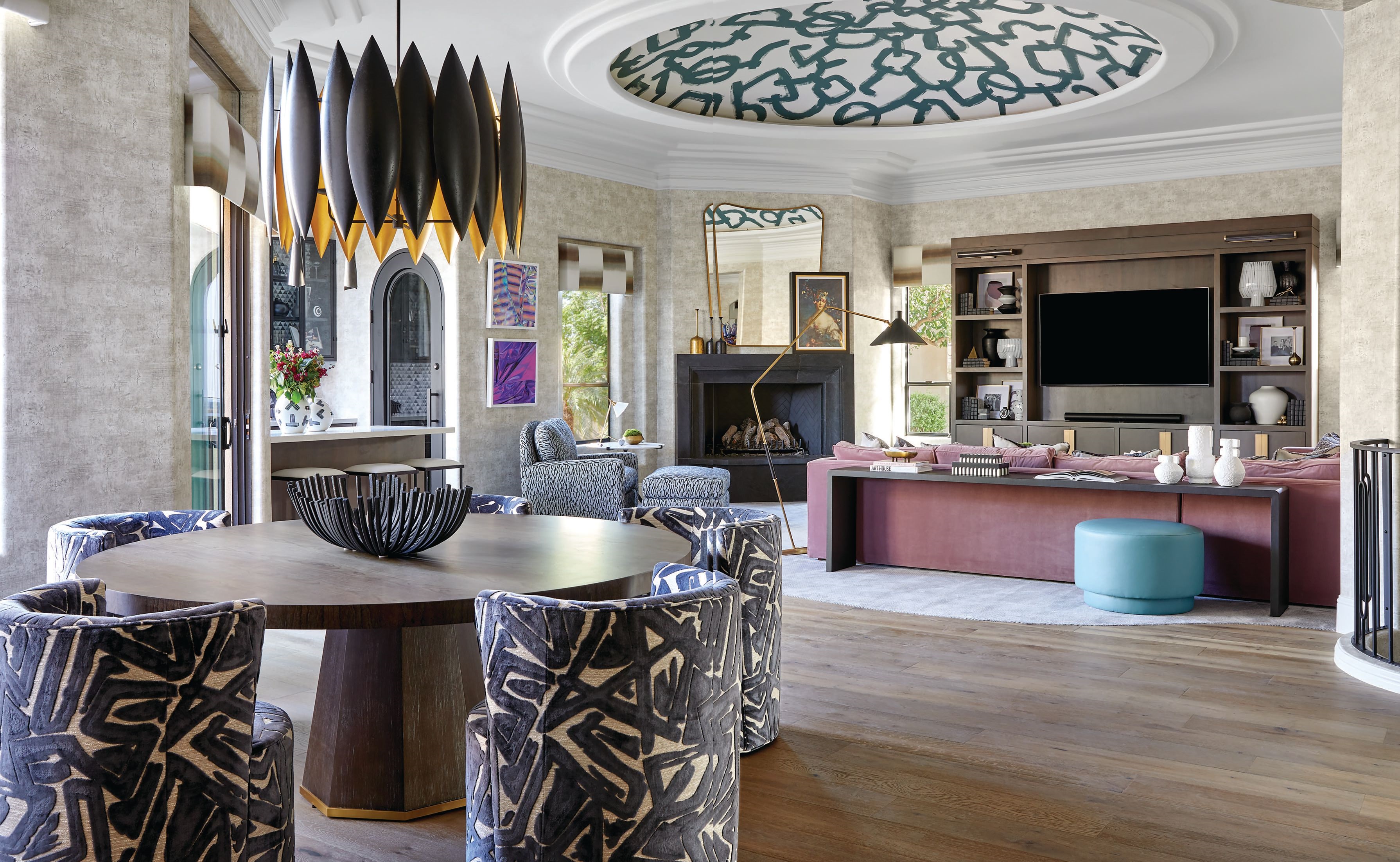Bold patterns and textures define the great room, where Simon chose graphic dining chairs and turquoise ottomans from CR Laine. The oversize floor lamp is from Visual Comfort, and the custom mauve sofa was designed by Britany Simon Design House and upholstered in S. Harris velvet. Photographed by Laura Moss
