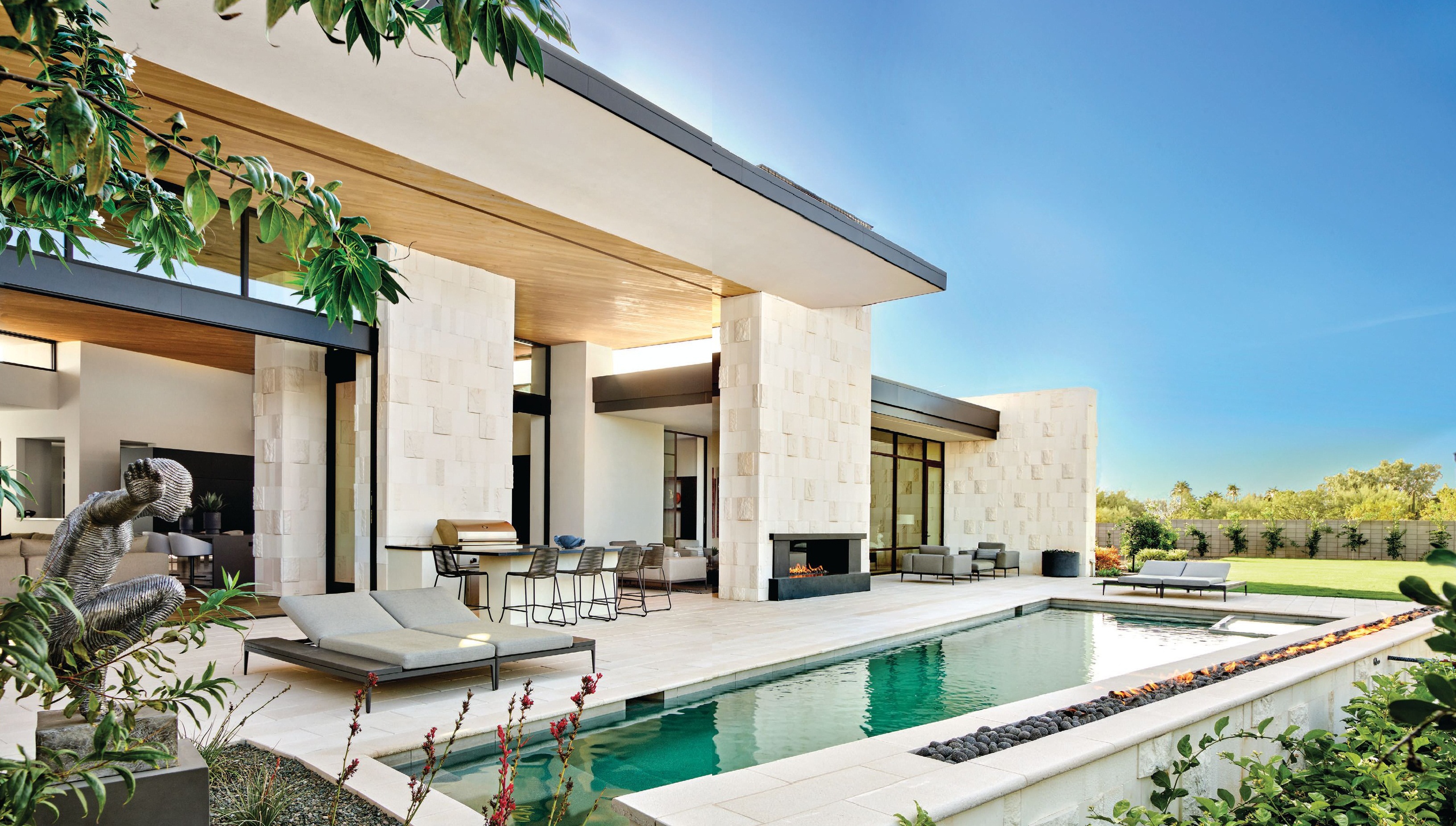 The home’s pool and patio area features streamlined furniture  from Gloster’s Grid collection and an outdoor kitchen outfitted with Wolf appliances. PHOTOGRAPHED BY WERNER SEGARRA