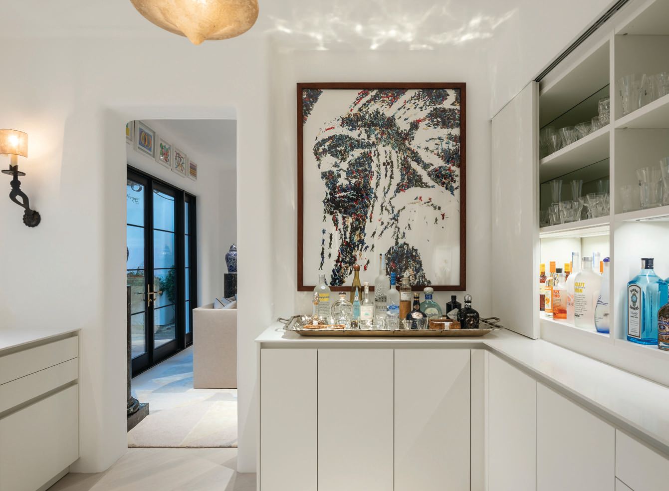 Equipped with cabinetry by Leicht, the bar area highlights several unique pieces, such as sconces from Formations, an antique alabaster pendant purchased in Paris at the Puces and a photograph by Vik Muniz PHOTOGRAPHED BY JOE COTITTA