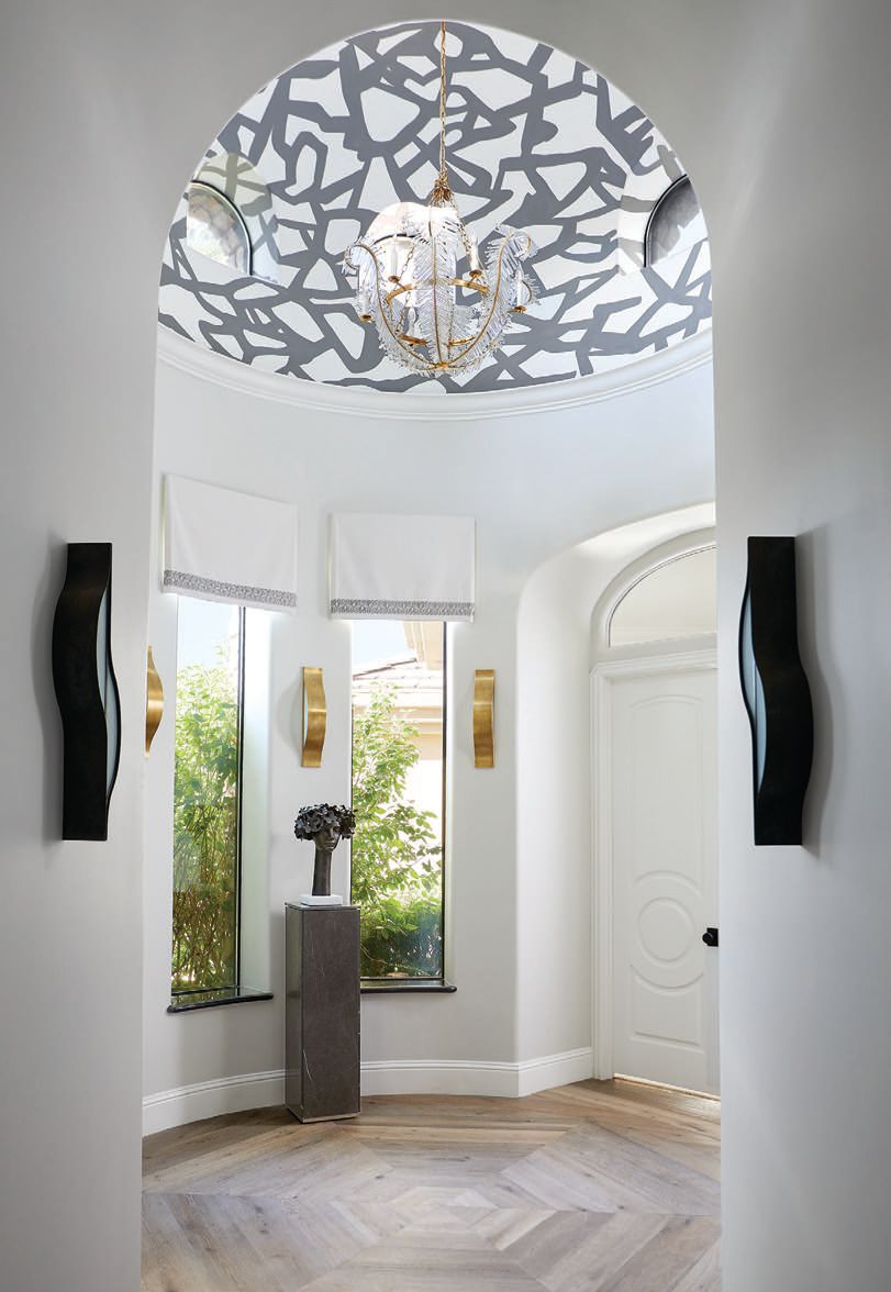 Simon added an edgy touch to the domed ceilings throughout the home, working with a local mural artist to create a one-of-a-kind graphic element to this vestibule. The pedestal and sculpture are by Global Views. Photographed by Laura Moss