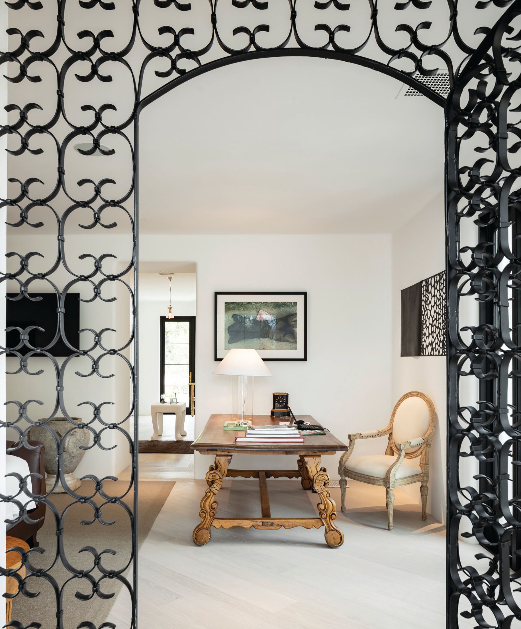 In lieu of a door, Boland created an eye-catching primary bedroom entrance made from reclaimed garden gates and surrounds found at a home in Scandinavia. The photograph over the antique desk was purchased from the collection of fashion photographer Mario Testino. Photographed by Joe Cotitta