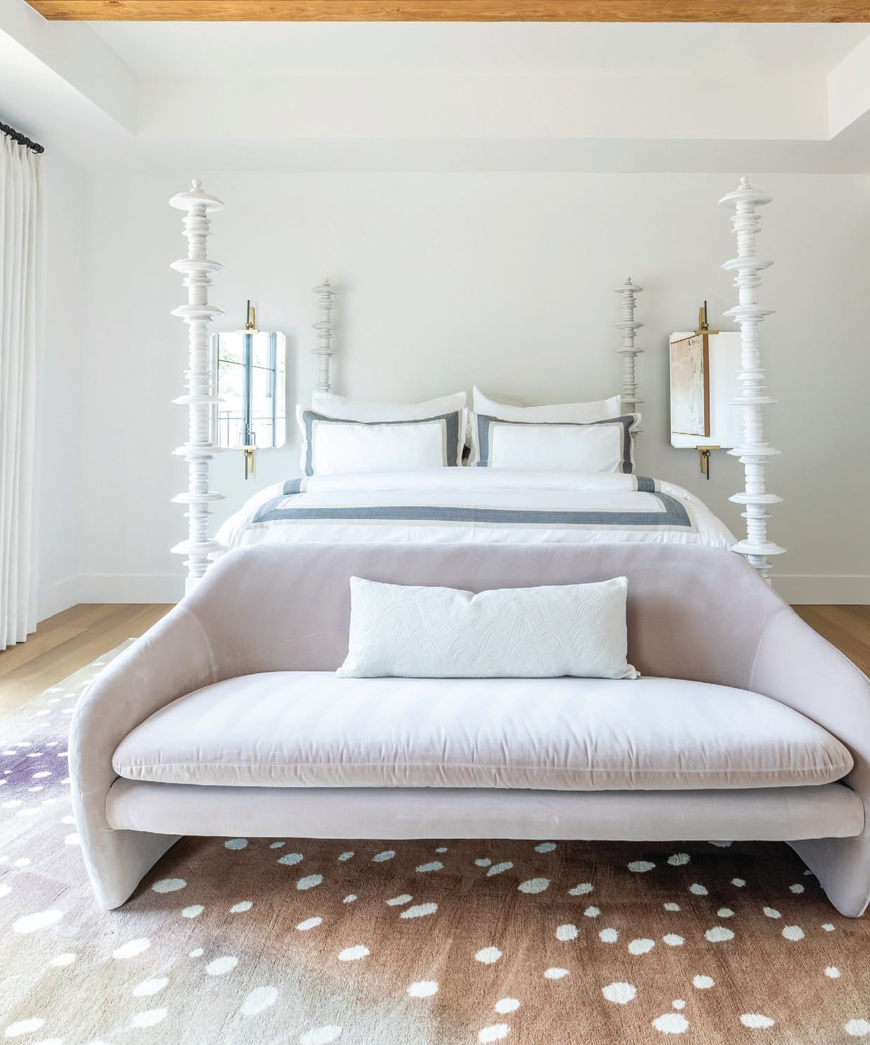 The light and airy primary bedroom is an oasis of calm, with a sculptural bed from Four Hands and a sofa and rug from CB2 taking center stage. Photographed by Flourish Photography