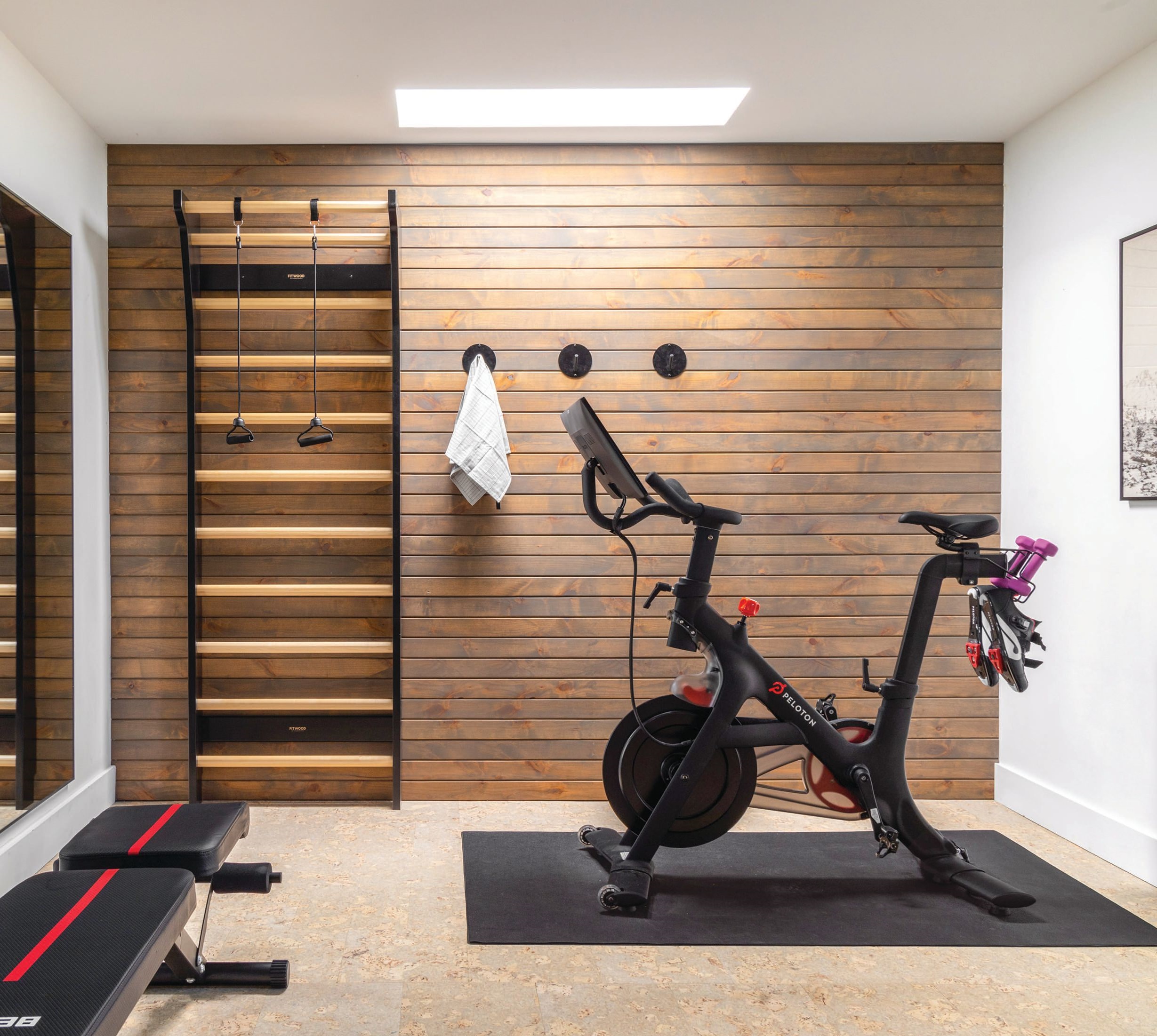 A custom slat wall by Luxury Woodworker and cork flooring by APC Cork warm up the gym area. Shelfology hooks and an art piece by Juniper Print Shop add a homey touch. Photographed by Kevin Brost