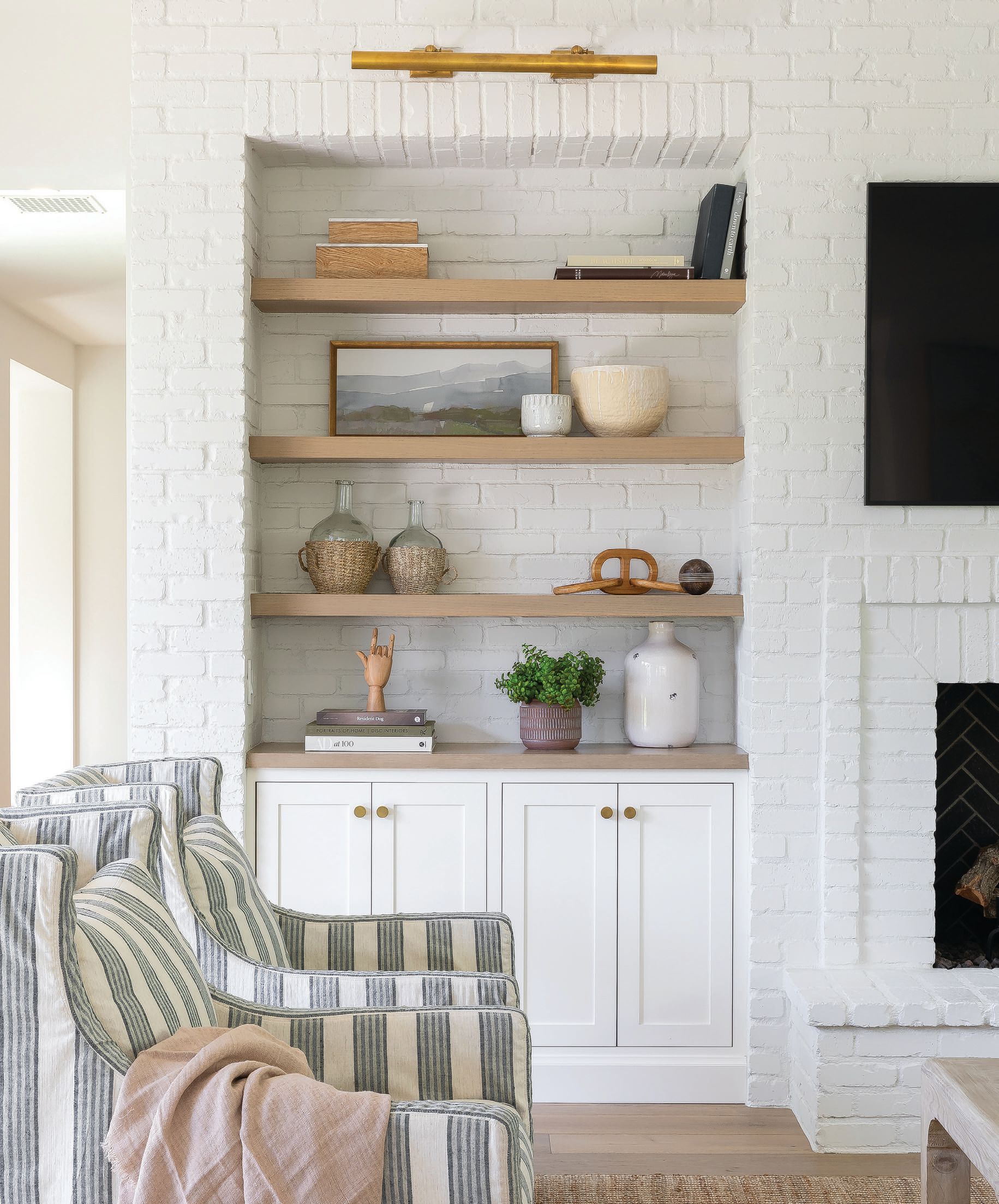 White painted brick and striped slipcovered chairs from Lee Industries set the tone for this casual family room.  Photographed by Ryan Garvin